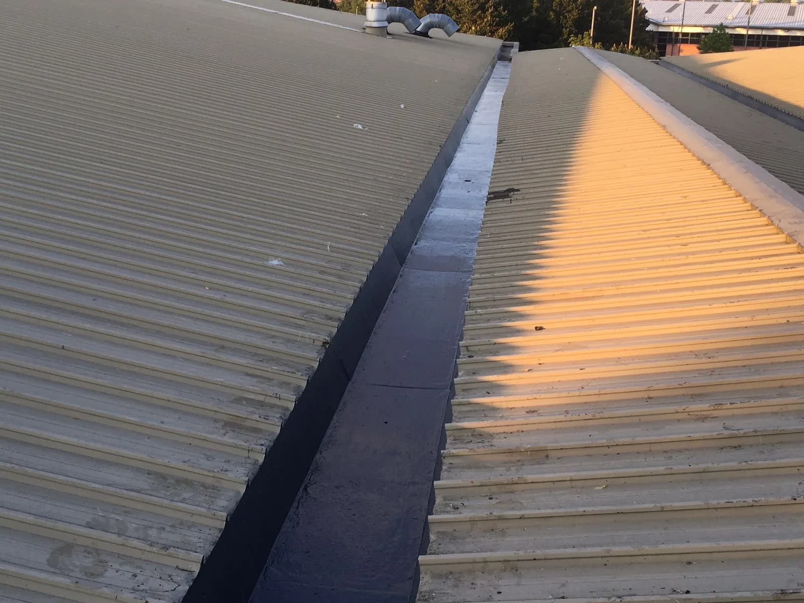 Newly repaired box gutter valley running along a commercial roof