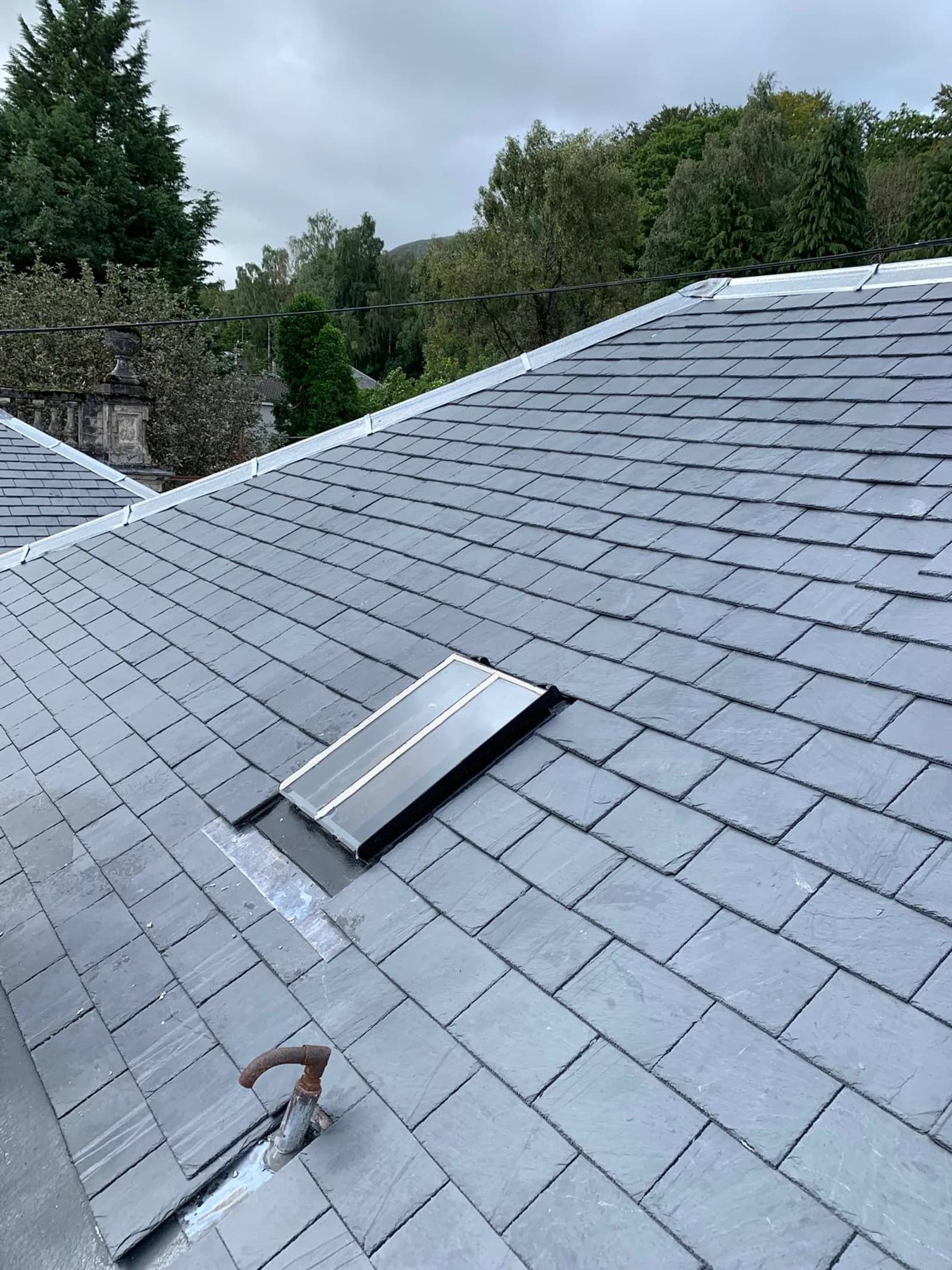 Roofer fitting natural slate tiles on a traditional Scottish roof